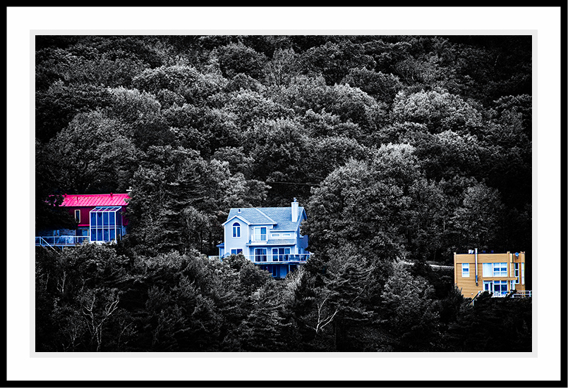 Three colorful houses aganist a black and white hill.
